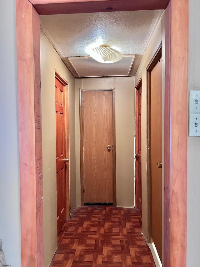 corridor with dark parquet flooring and a textured ceiling