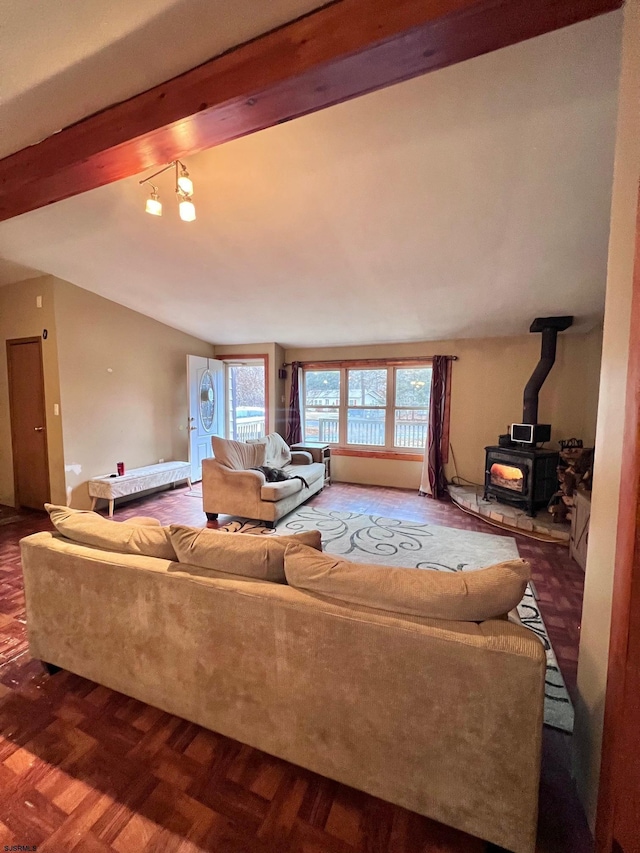 living room featuring lofted ceiling with beams, dark parquet flooring, and a wood stove