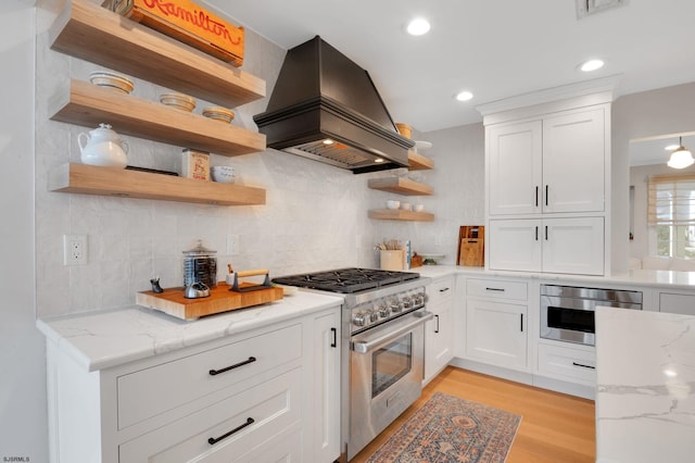 kitchen featuring white cabinetry, light stone countertops, custom exhaust hood, and high end stove