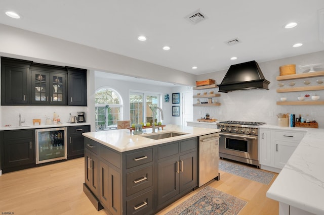 kitchen with sink, appliances with stainless steel finishes, wine cooler, custom range hood, and white cabinets