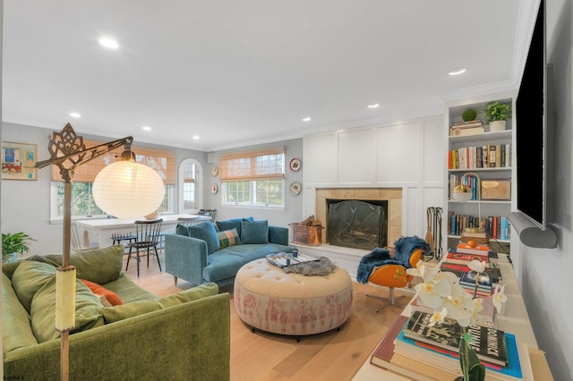 living room with crown molding, a tile fireplace, and hardwood / wood-style flooring