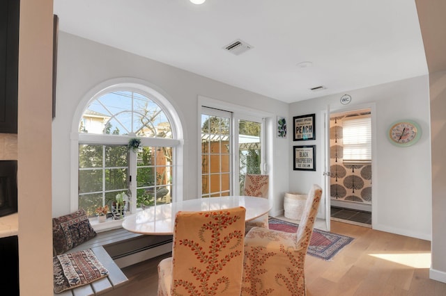 dining area featuring a healthy amount of sunlight, light hardwood / wood-style floors, and a baseboard heating unit