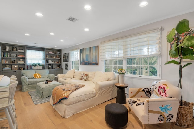 living room with ornamental molding, plenty of natural light, and light wood-type flooring