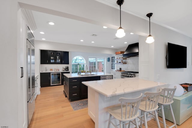 kitchen with pendant lighting, sink, a breakfast bar, custom range hood, and a kitchen island