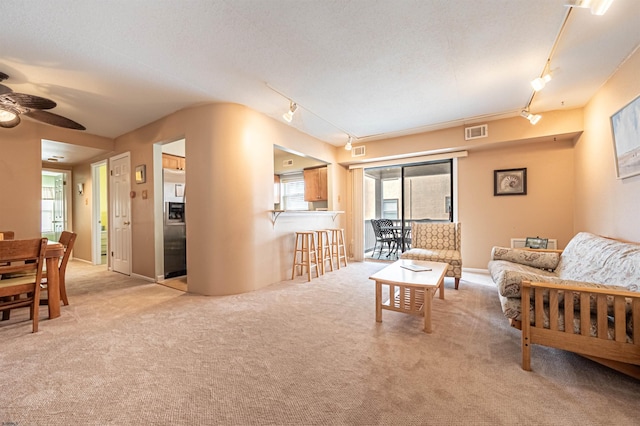 carpeted living room with a textured ceiling, rail lighting, and ceiling fan