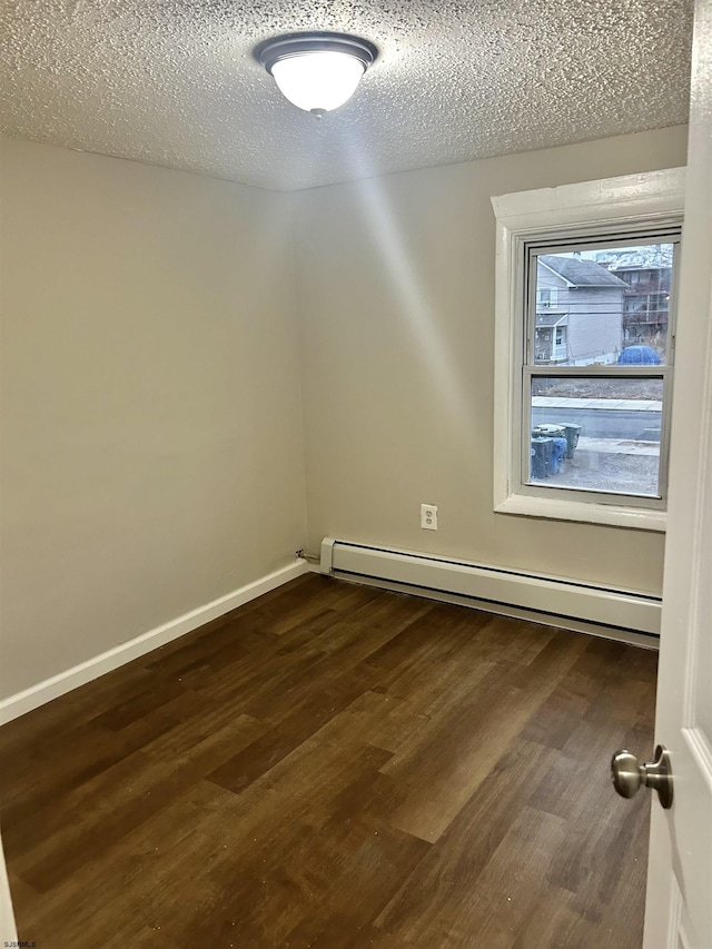 empty room featuring baseboard heating, dark wood-type flooring, and a textured ceiling