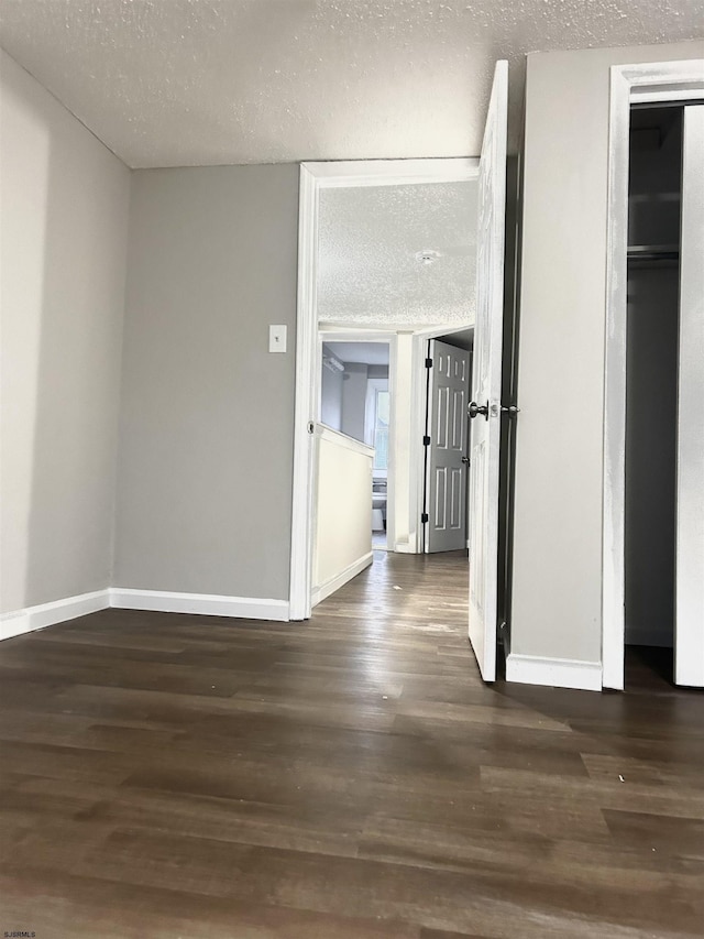 hallway with dark wood-type flooring and a textured ceiling