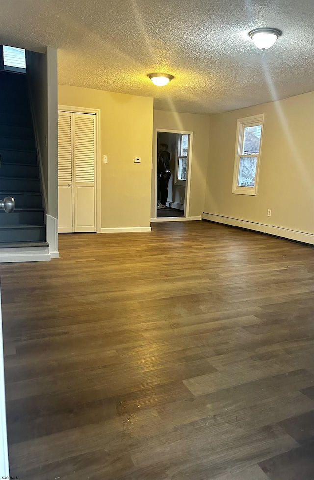 unfurnished room featuring dark hardwood / wood-style floors, a textured ceiling, and baseboard heating