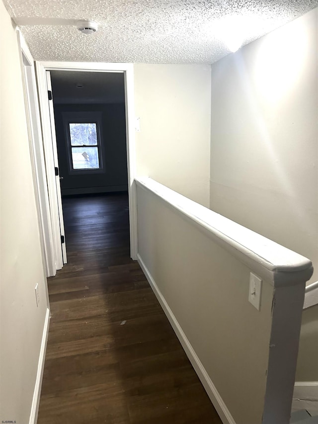 hallway featuring dark hardwood / wood-style flooring and a textured ceiling