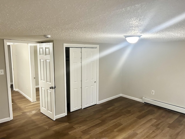 unfurnished bedroom featuring a baseboard radiator, dark hardwood / wood-style floors, a closet, and a textured ceiling