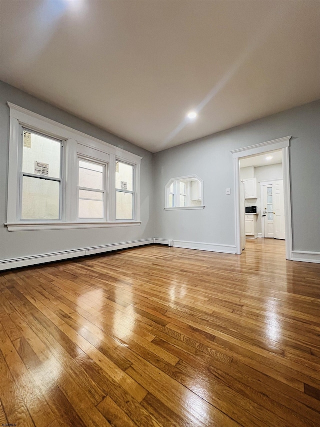 unfurnished living room with hardwood / wood-style flooring and a baseboard radiator