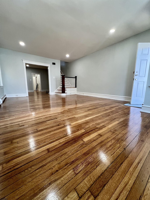 unfurnished living room with hardwood / wood-style flooring and a baseboard heating unit