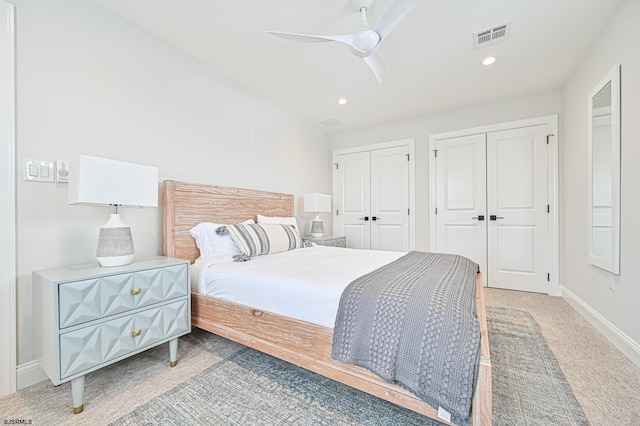 bedroom with two closets, carpet floors, and ceiling fan