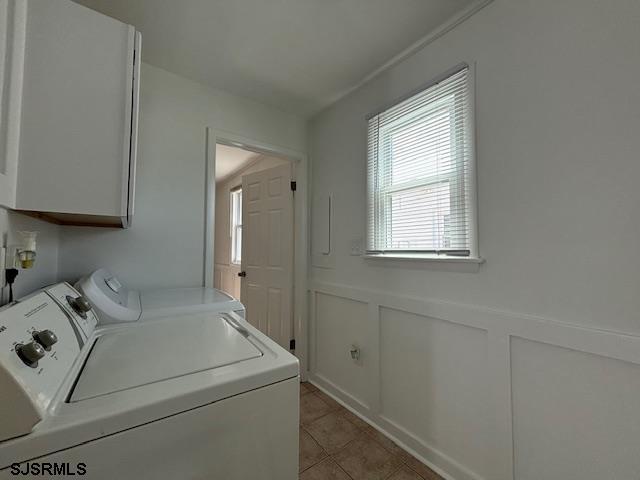 washroom with cabinets, washing machine and dryer, and light tile patterned floors