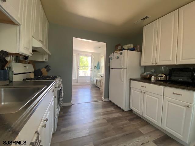 kitchen featuring light wood-style floors, freestanding refrigerator, white cabinetry, and gas range