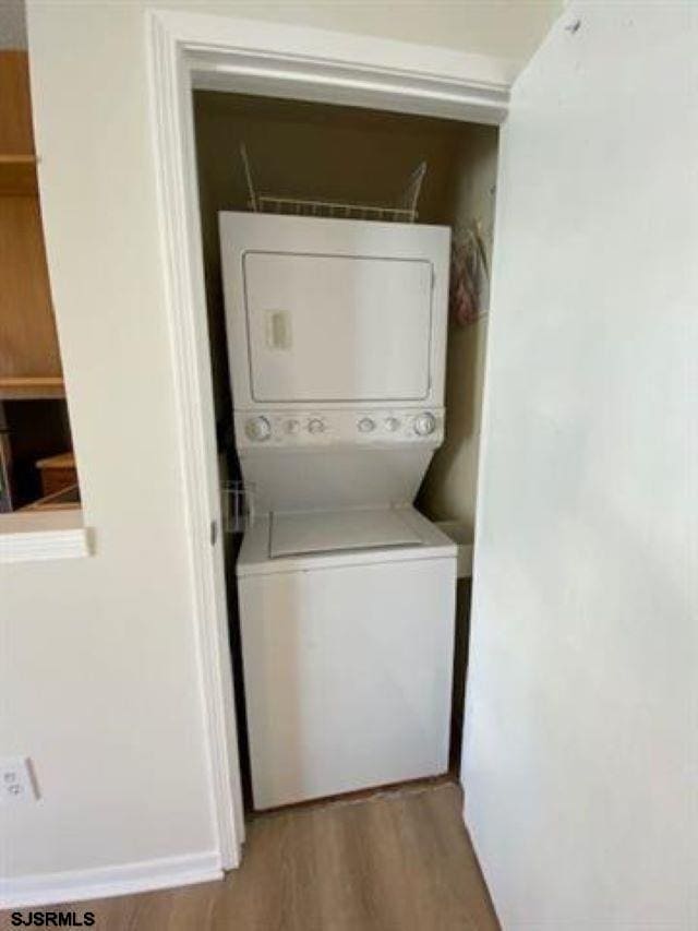 clothes washing area with stacked washer and dryer and light hardwood / wood-style flooring