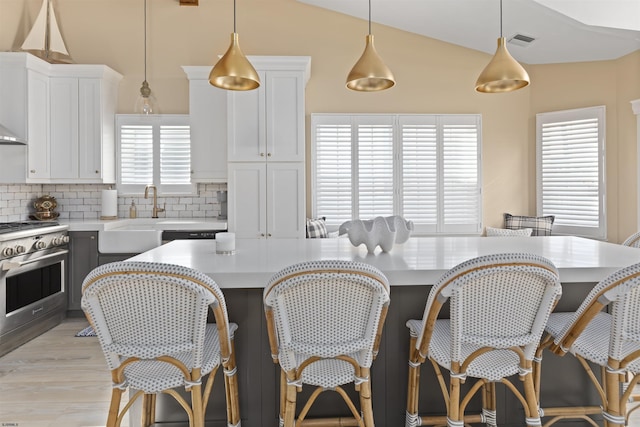 kitchen featuring high end stove, tasteful backsplash, light countertops, and lofted ceiling