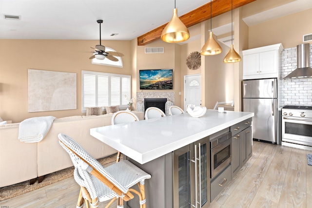 kitchen with stainless steel appliances, light wood-type flooring, a fireplace, and visible vents