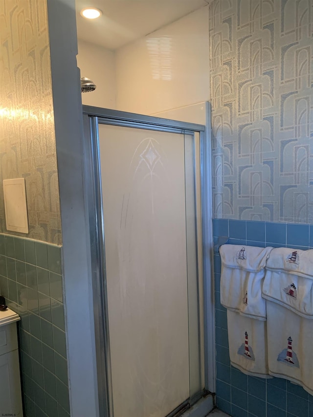 bathroom with walk in shower, vanity, and tile walls