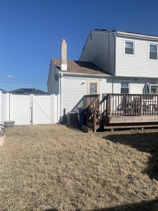 rear view of house featuring a wooden deck, a lawn, and central air condition unit