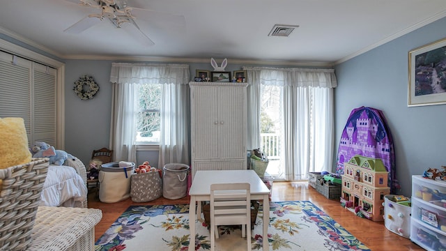 rec room with wood-type flooring, ornamental molding, and ceiling fan