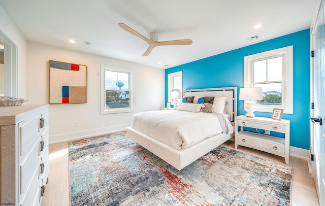 bedroom featuring ceiling fan, multiple windows, and light hardwood / wood-style flooring