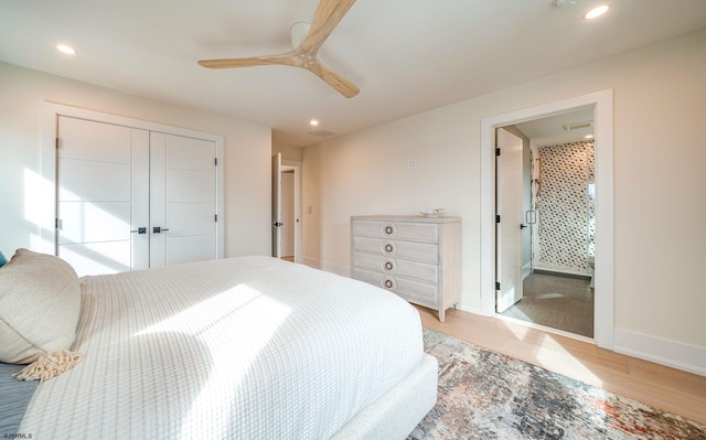 bedroom featuring ensuite bath, light hardwood / wood-style flooring, a closet, and ceiling fan