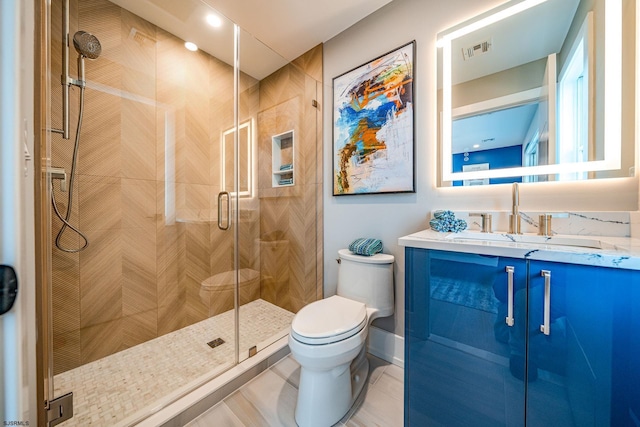 bathroom with a shower with door, vanity, tile patterned flooring, and toilet