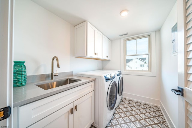 clothes washing area with cabinets, sink, and washer and dryer