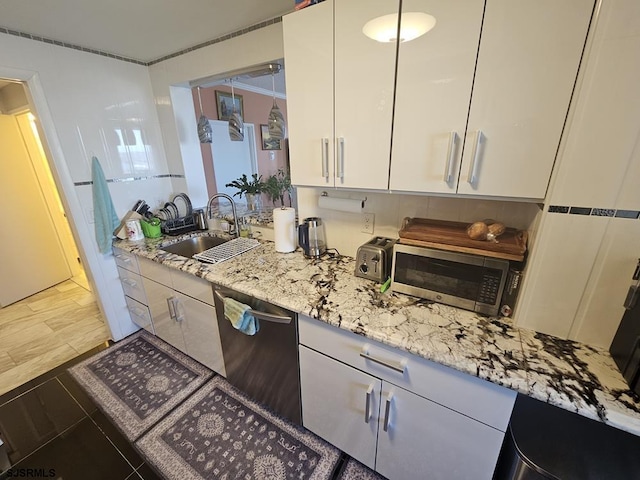 kitchen featuring appliances with stainless steel finishes, light stone countertops, sink, and white cabinets