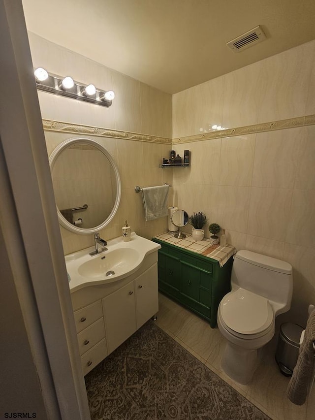 bathroom with tile walls, vanity, tile patterned floors, and toilet