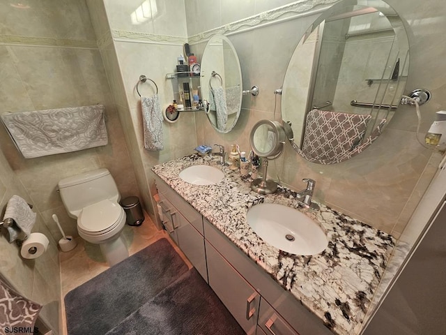 bathroom with vanity, toilet, and tile walls