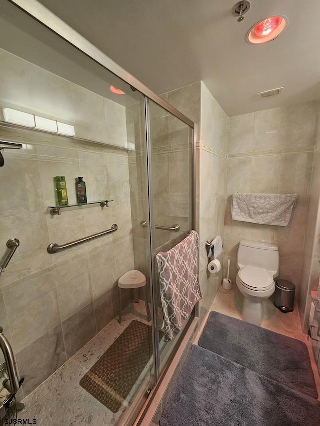 bathroom featuring tile patterned floors, toilet, and a shower with door