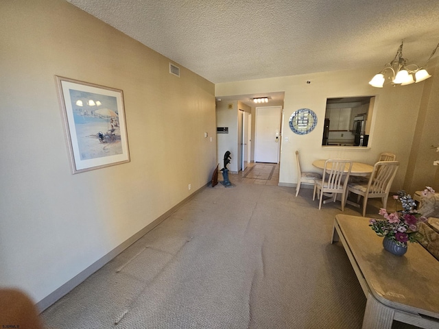 living room featuring a chandelier, carpet, and a textured ceiling