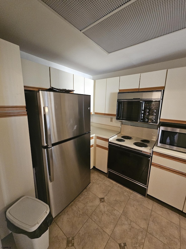 kitchen with stainless steel appliances, light tile patterned floors, and white cabinets