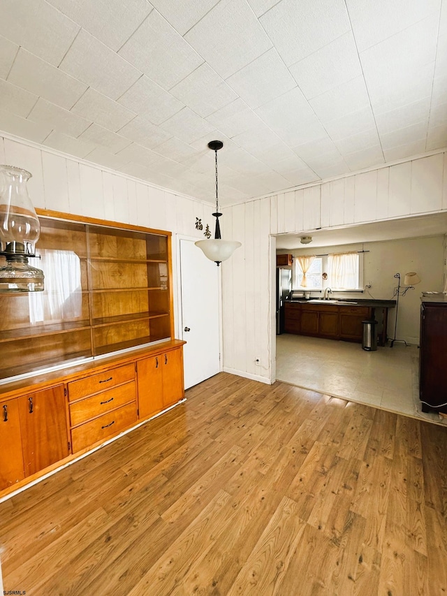 kitchen with stainless steel refrigerator, decorative light fixtures, and light hardwood / wood-style flooring