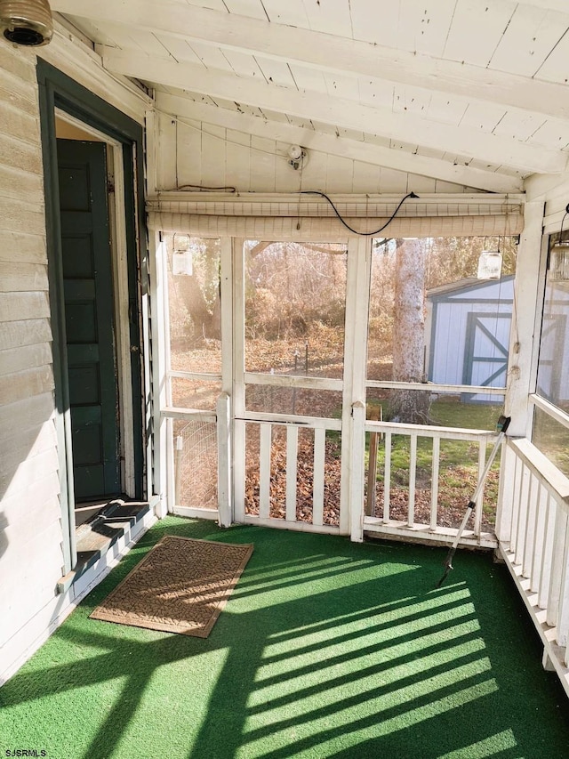 unfurnished sunroom featuring vaulted ceiling, a healthy amount of sunlight, and wood ceiling