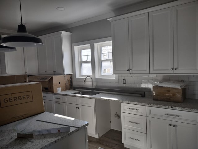 kitchen with sink, white cabinets, backsplash, and decorative light fixtures