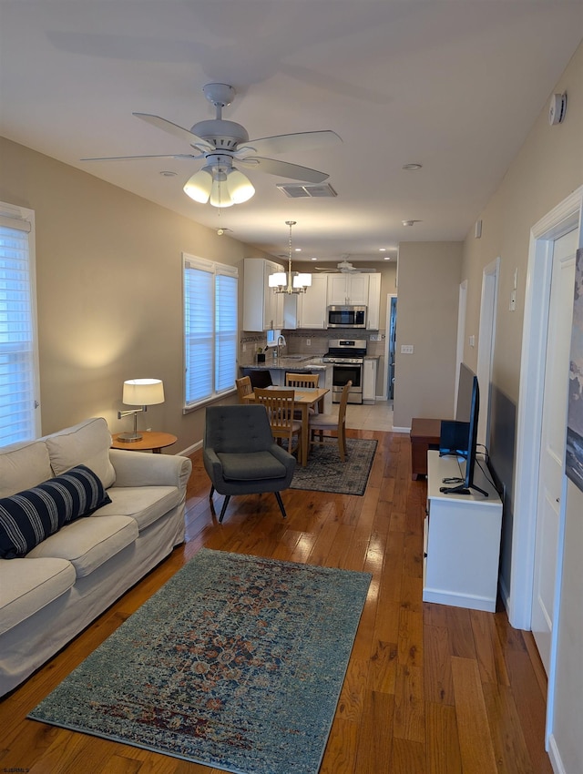 living room featuring sink, hardwood / wood-style flooring, and ceiling fan with notable chandelier