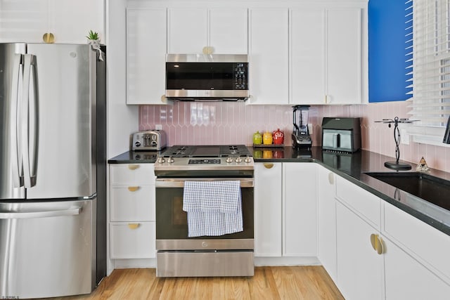 kitchen with sink, white cabinetry, appliances with stainless steel finishes, light hardwood / wood-style floors, and backsplash