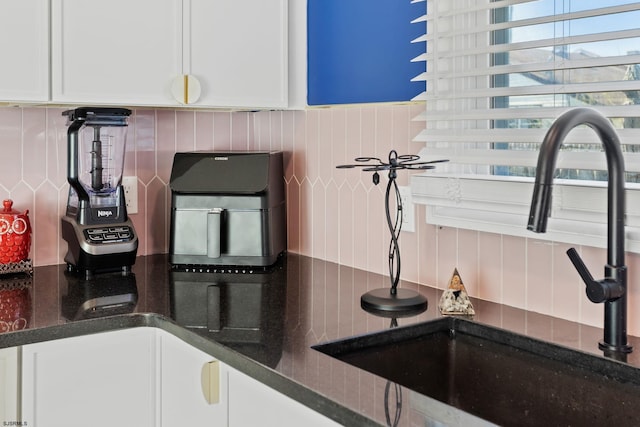 kitchen with dark stone countertops, sink, decorative backsplash, and white cabinets