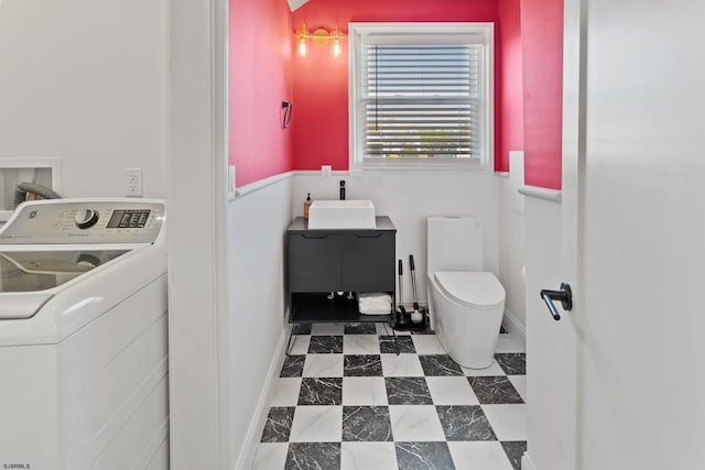 bathroom featuring toilet, washer / clothes dryer, and sink