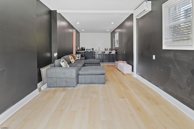 living room featuring a healthy amount of sunlight, a wall unit AC, and light hardwood / wood-style floors