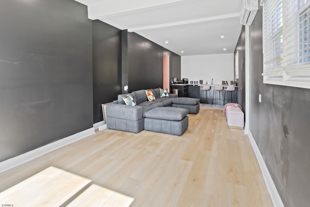 living room with beam ceiling, a wall mounted AC, and light hardwood / wood-style flooring