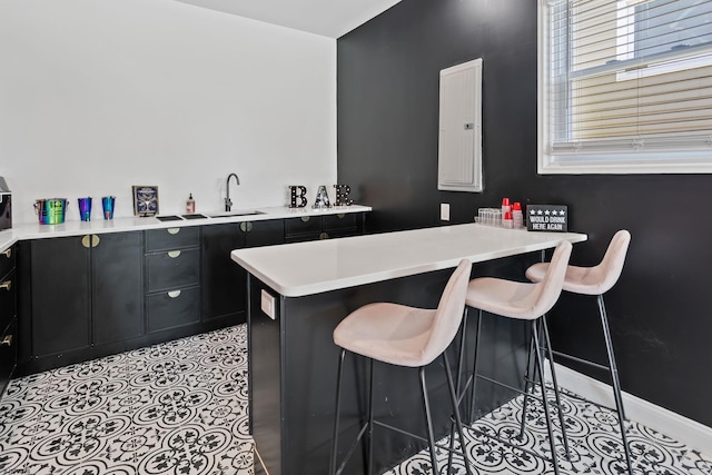 kitchen with light tile patterned flooring, sink, and a kitchen breakfast bar