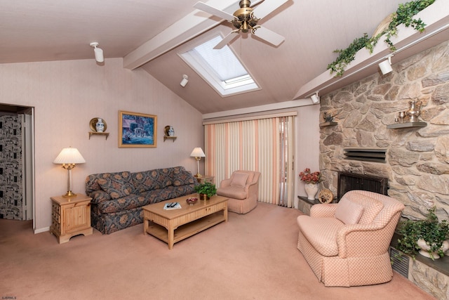 living room with lofted ceiling with skylight, a stone fireplace, carpet flooring, and ceiling fan