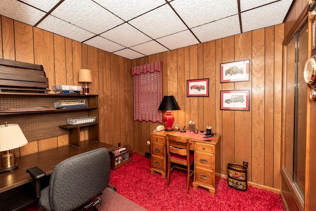 home office featuring a paneled ceiling, wood walls, and carpet