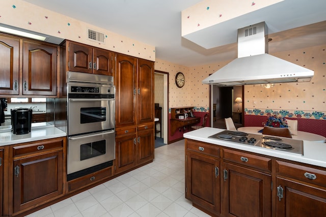 kitchen featuring island exhaust hood, stovetop, double oven, and dark brown cabinetry