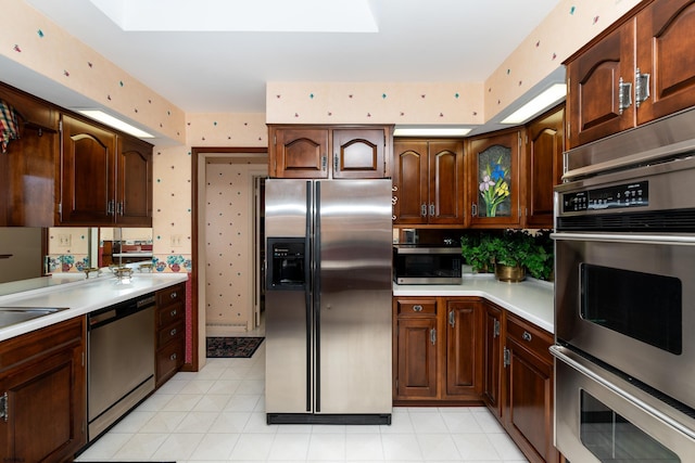 kitchen with a skylight, stainless steel appliances, and light tile patterned flooring