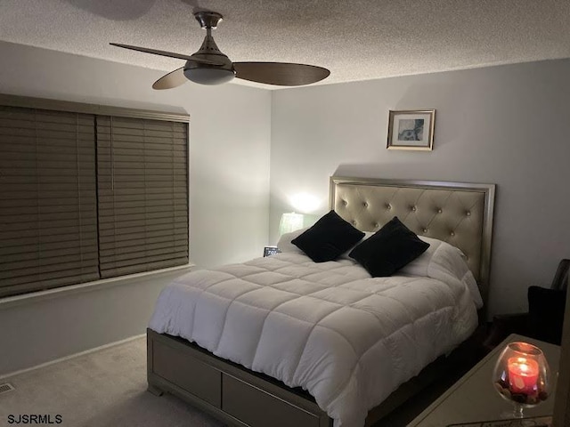 bedroom featuring ceiling fan, light colored carpet, and a textured ceiling